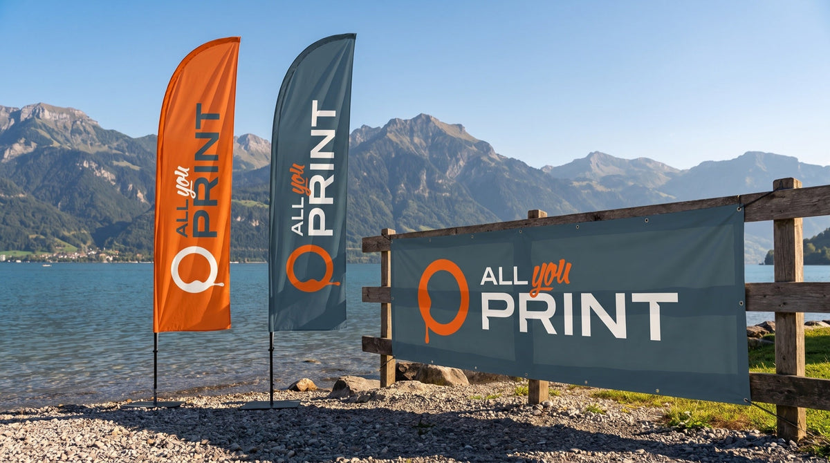 Beach flags and a banner with the All You Print logo on the shore of a Swiss lake